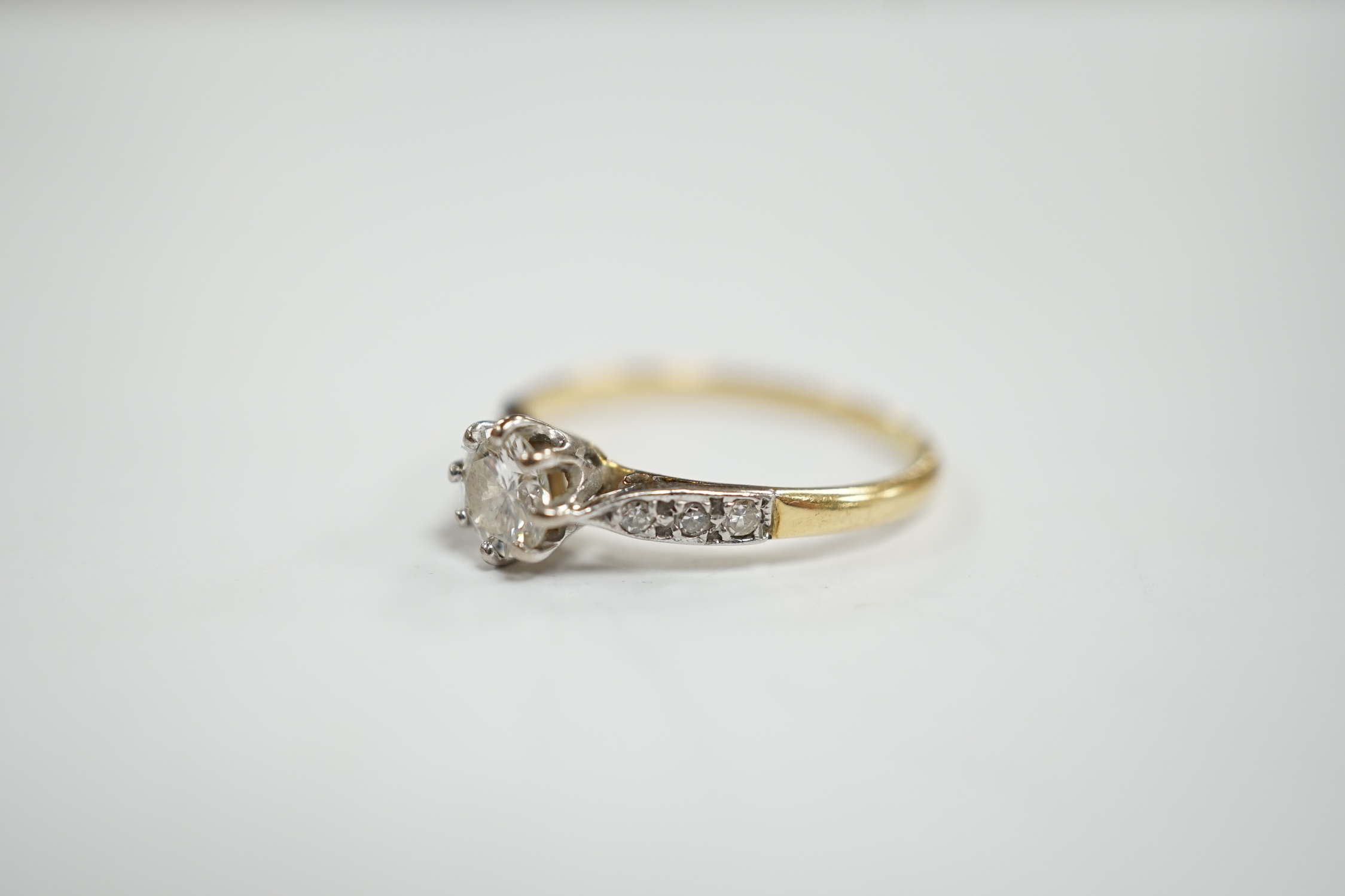 An 18ct and single stone diamond set ring, with diamond chip set shoulders, size M, gross weight 1.9 grams.